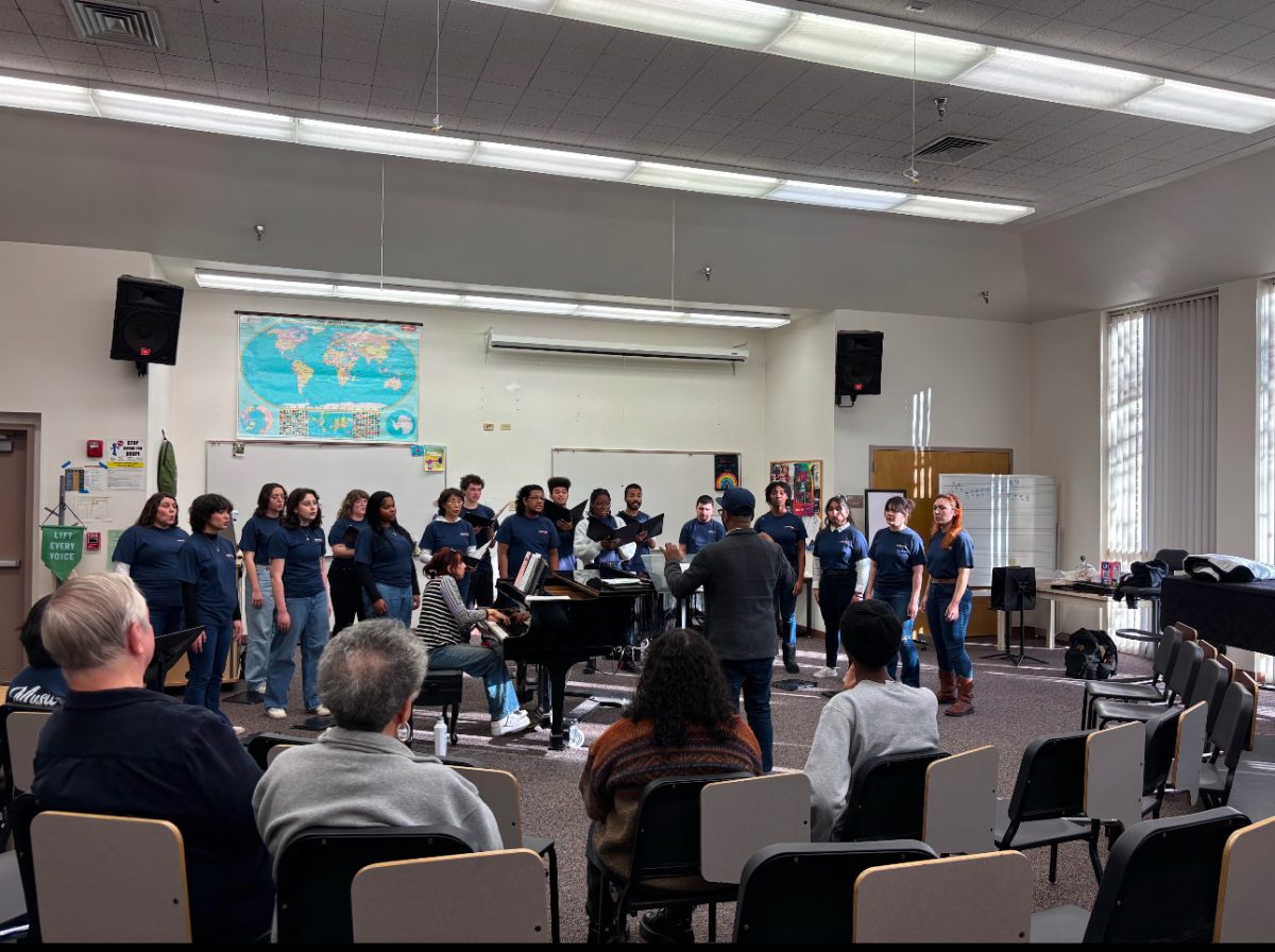 Omari Tau conducts the combined choirs on Dec. 3 in room M300 for a half-hour dress rehearsal. Both choirs practiced for the last time before their main and last performance on Dec. 5 before winter recess.